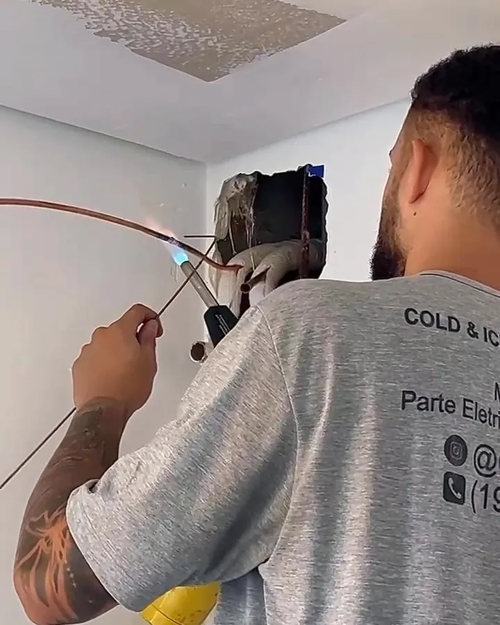 Técnico com a camiseta da Cold&Ice passando a infraestrutura do ar condicionado num apartamento