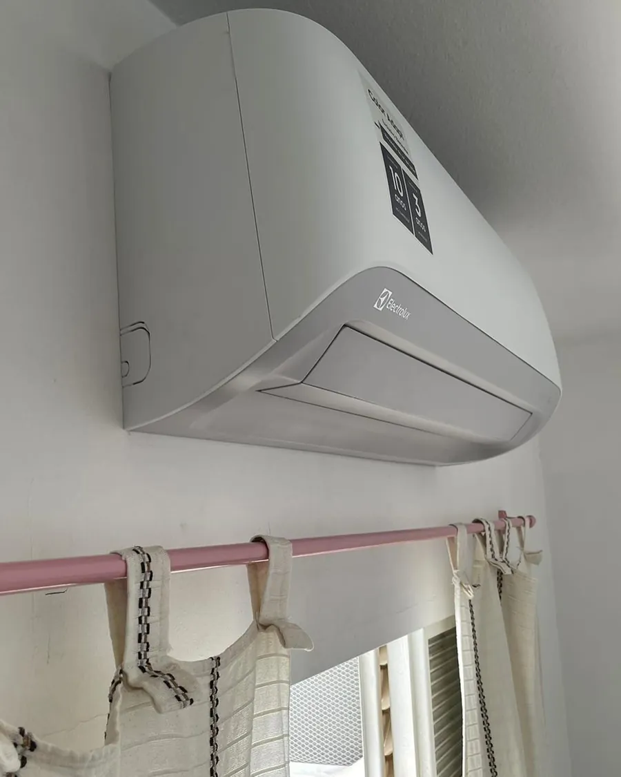 Ar condicionado Electrolux instalado no alto da parede, acima da janela