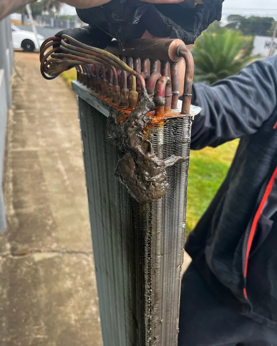 Técnico limpando a serpentina de um ar condicionado piso teto desmontado
