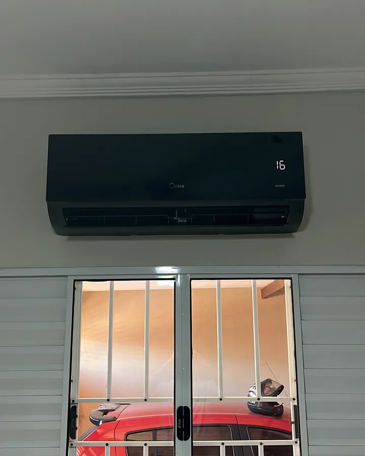 Ar condicionado Springer Midea preto com frente de vidro instalado acima da janela